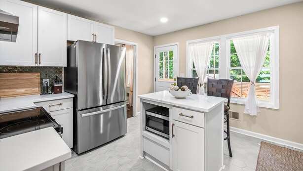 A modern kitchen with stainless steel appliances, white cabinetry, and a view of the outdoors. - 5Br Lux Green Manor w/Movie Room, Fenced Yard & Sleeps 12 (Raleigh)
