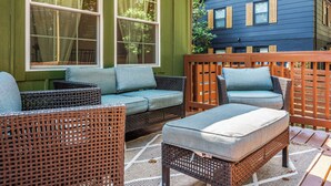 A patio with wicker furniture and a view of a blue house. - 5Br Lux Green Manor w/Movie Room, Fenced Yard & Sleeps 12 (Raleigh)