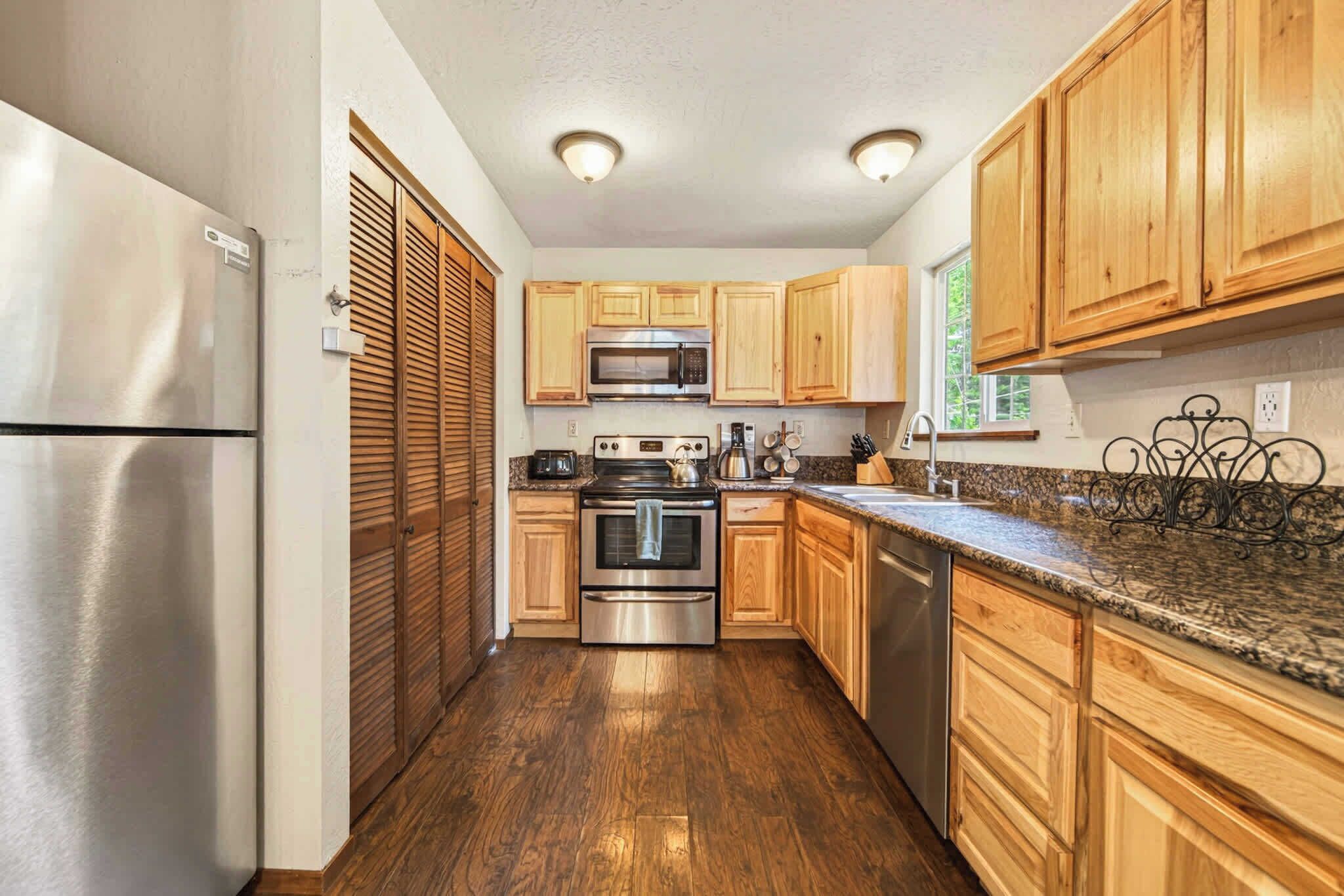 A compact kitchen with wooden cabinets, stainless steel appliances, and granite countertops.