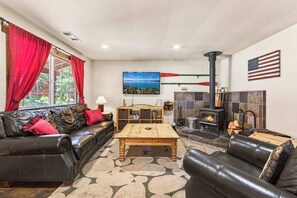 Ein Wohnzimmer mit Kamin, Ledersofas, einem Holztisch und einem Fernseher.