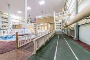 Un atrium interior de diversos nivells amb un passeig central, balcons i una zona de piscina.