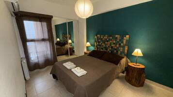 A bedroom with a bed, bedside lamps, a mirror, and a wall with a checkered pattern.