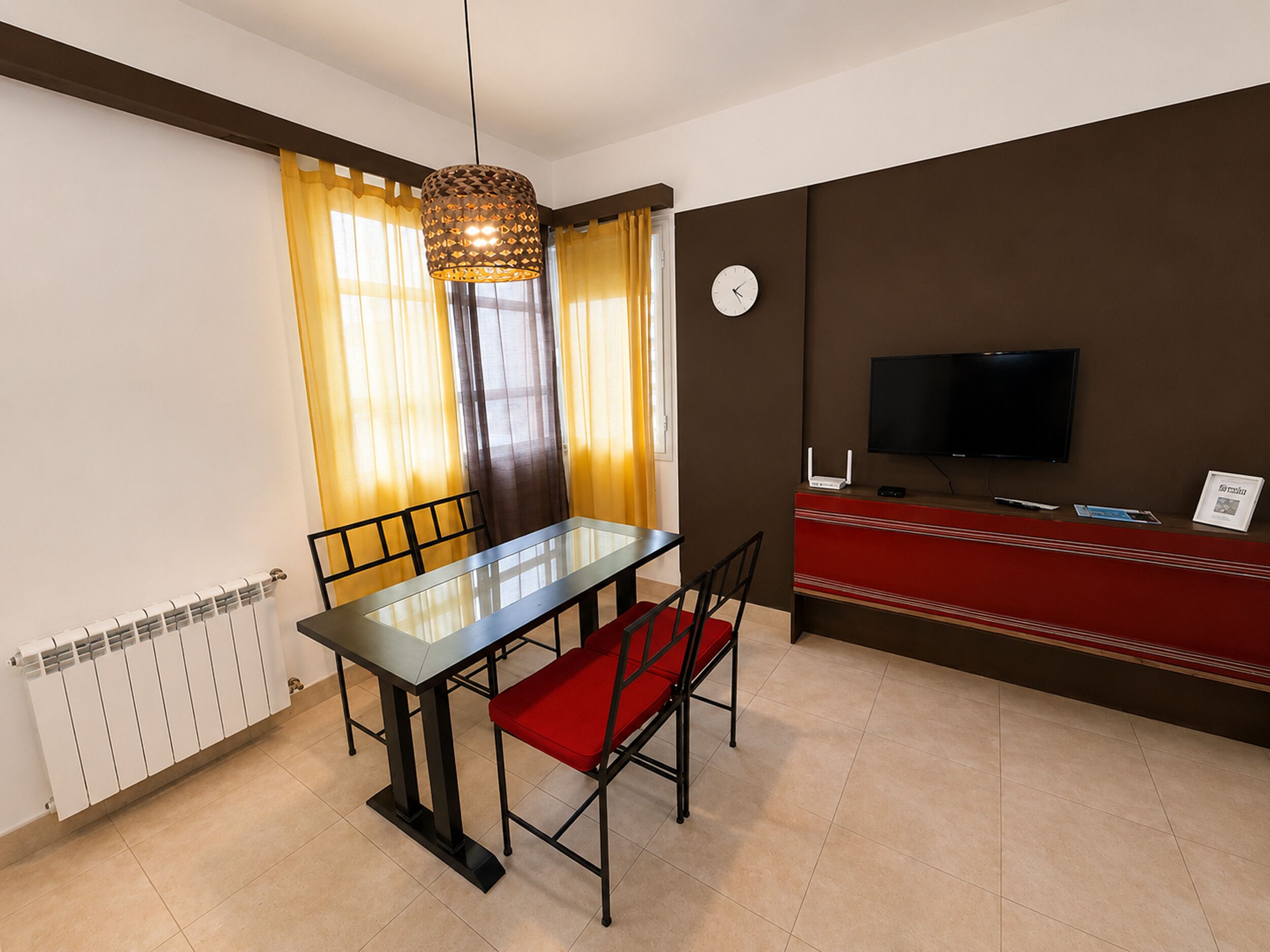 A modern living room with a dining table, chairs, a television, and a red sofa.