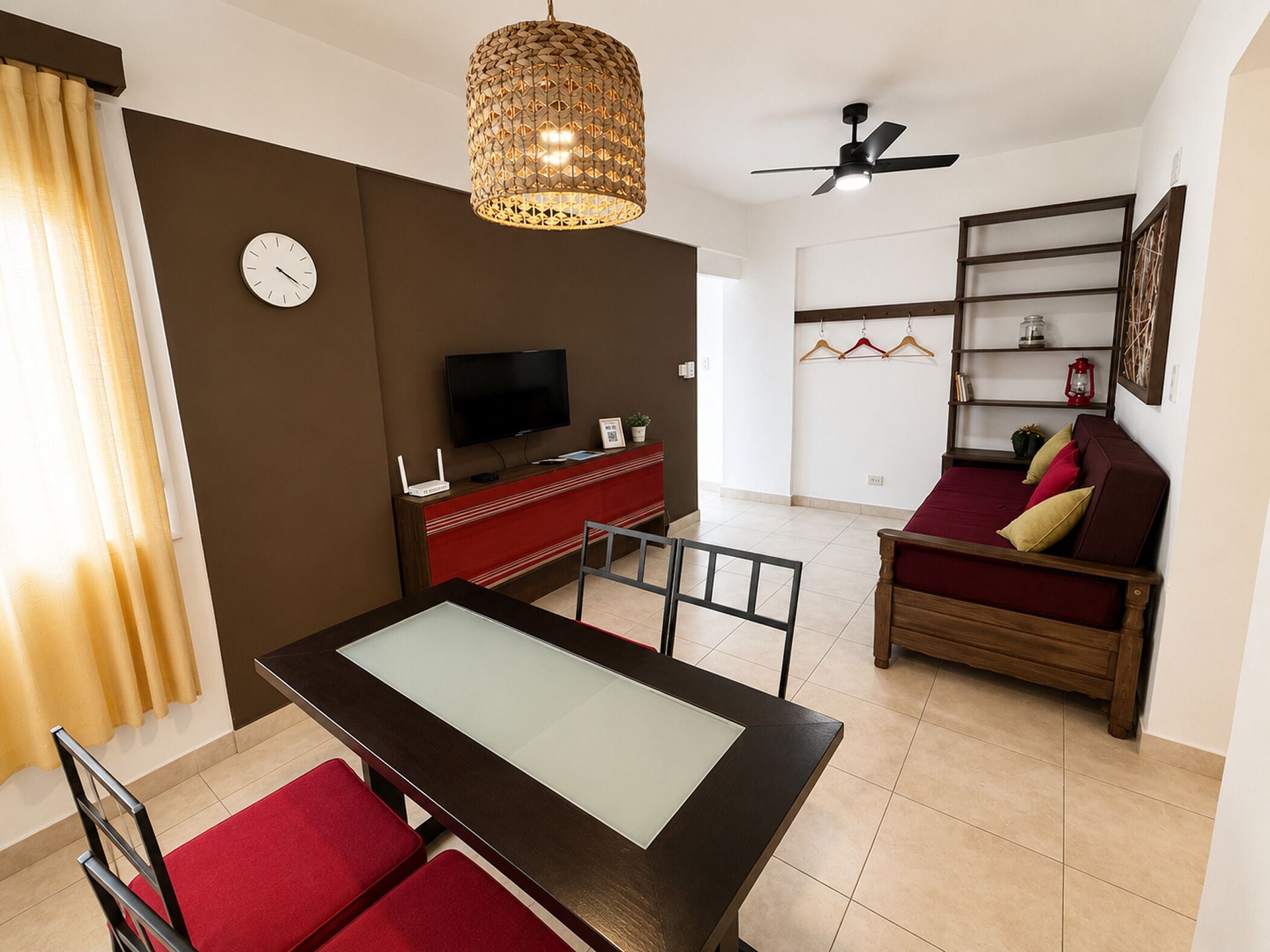 A modern living room with a dining table, sofa, TV, and a decorative hanging light fixture.
