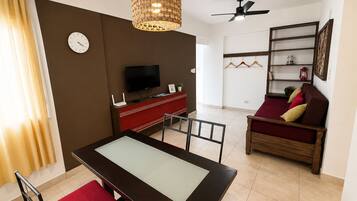 A modern living room with a dining table, sofa, TV, and a decorative hanging light fixture.