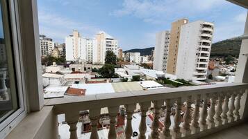 A balcony with a view of a cityscape, including several high-rise buildings and a mountain in the distance.