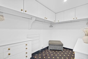 A white room with a patterned floor, a grey bench, and white cabinets with gold handles. - Ocean Vista Penthouse - Private Pool & BBQ, WiFi (Surfers Paradise)