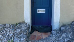 A blue door with a 'STABLE' sign, a wall-mounted light, and a stone-paved entrance.