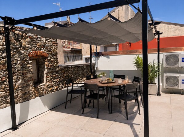 A patio with a stone wall, a table with chairs, and two air conditioning units.