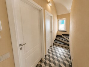 A hallway with a geometric patterned floor, white doors, and a window with a view.