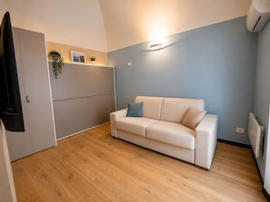 A compact living space with a sofa, a built-in wardrobe, and a wall-mounted light fixture.