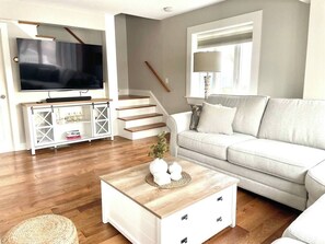 Ein Wohnzimmer mit Fernseher, Sofa, Couchtisch und Treppe.