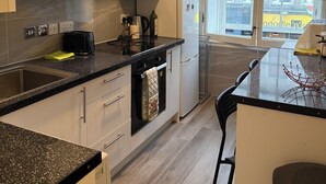 Een moderne keuken met een inbouwoven, een koffiezetapparaat en een raam met uitzicht op gebouwen.