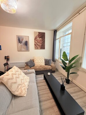 Ein modernes Wohnzimmer mit einer Couch, einem Couchtisch und einem großen Fenster.