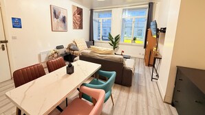 Een moderne woonkamer met een bank, een eettafel en een televisie.