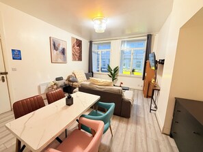Ein modernes Wohnzimmer mit einer Couch, einem Esstisch und einem Fernseher.