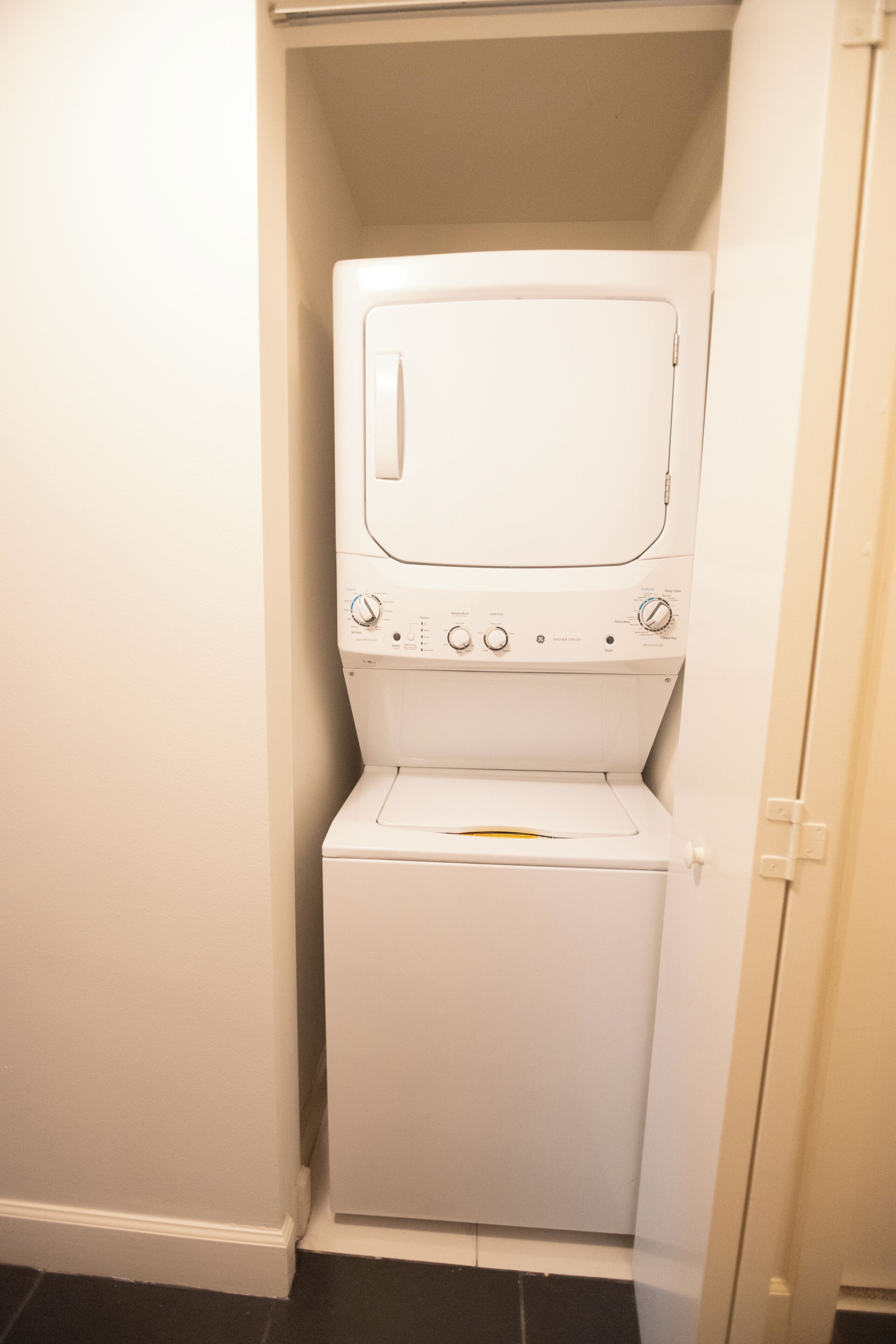 Lavadora y secadora blanca, compacta, montada en la pared, con panel de control y múltiples ajustes.