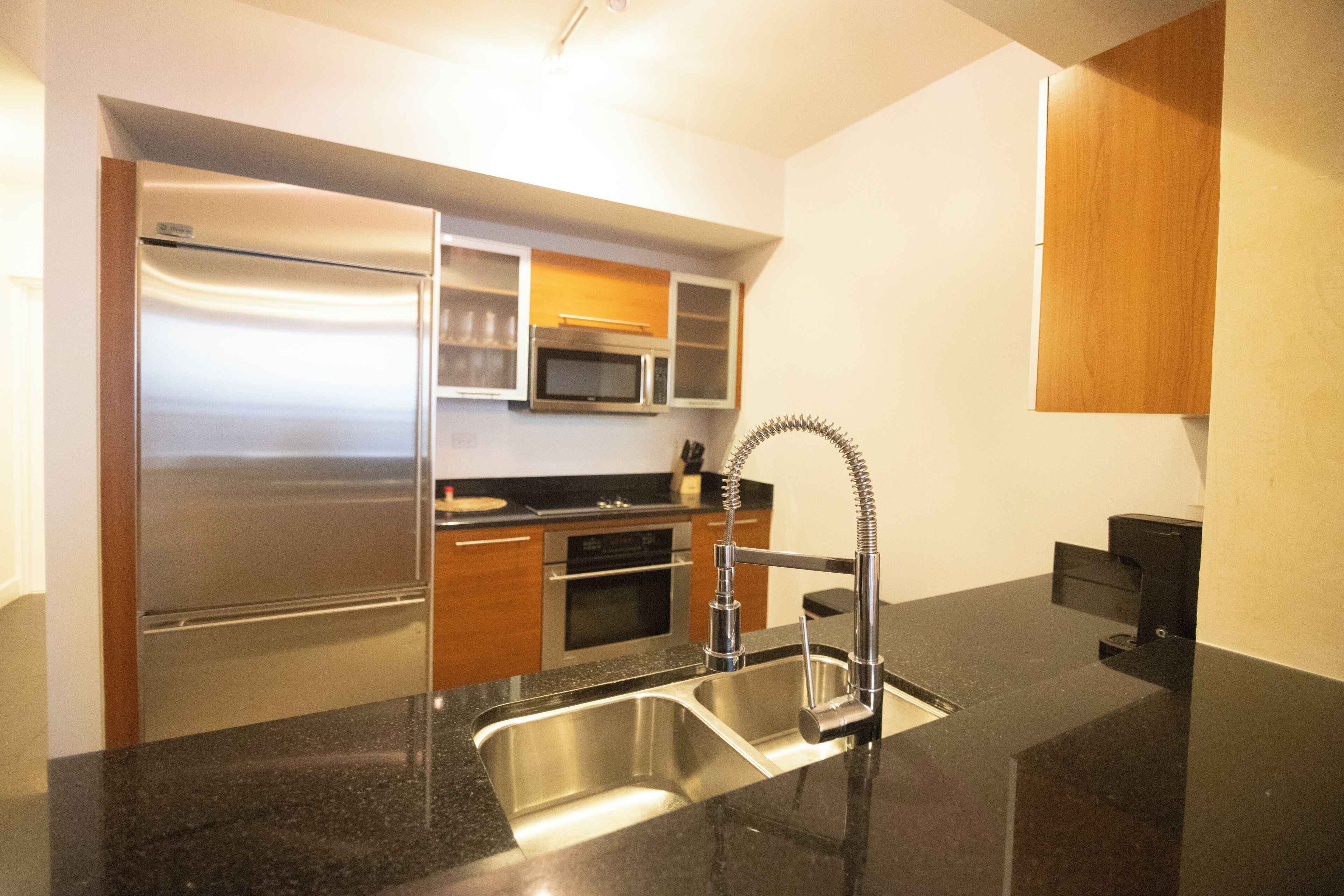 A modern kitchen with stainless steel appliances, a granite countertop, and wooden cabinets.
