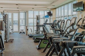 Ein Fitnessstudio mit Laufbändern, Kraftgeräten und einem großen Fenster.