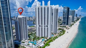 A high-rise hotel with a pool and beach view, surrounded by other tall buildings and a coastline. - Exclusive Trump Beachfront Condo (Sunny Isles Beach)