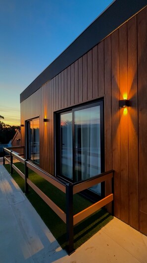 A modern building with wooden paneling, large glass windows, and outdoor seating.