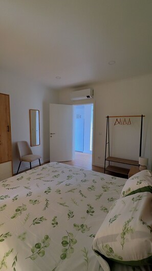 Une chambre à coucher comprenant un lit, une chaise, une armoire, un miroir et un porte-vêtements.