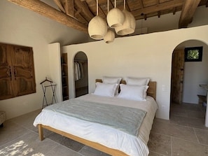 Ein Schlafzimmer mit einem großen Bett, Holzbalken und Pendelleuchten.