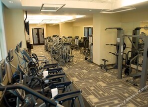 Ein Fitnessstudio mit Laufbändern, Kraftgeräten und einer Spiegelwand.