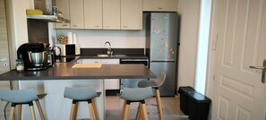 Una cocina moderna con una isla central, taburetes de bar, un refrigerador y un lavamanos.