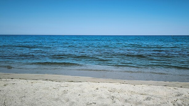 Een strand met helderblauw water en een zandstrand.