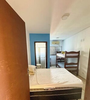 Ein gemütlicher Raum mit Bett, Schreibtisch, Stuhl, Fenster und Tür.
