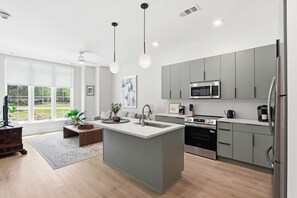 Een moderne keuken met een centraal eiland, roestvrijstalen apparatuur en een groot raam met uitzicht op de omgeving.