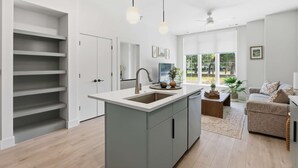 Una cocina moderna con una isla central, estanterías empotradas e iluminación colgante.