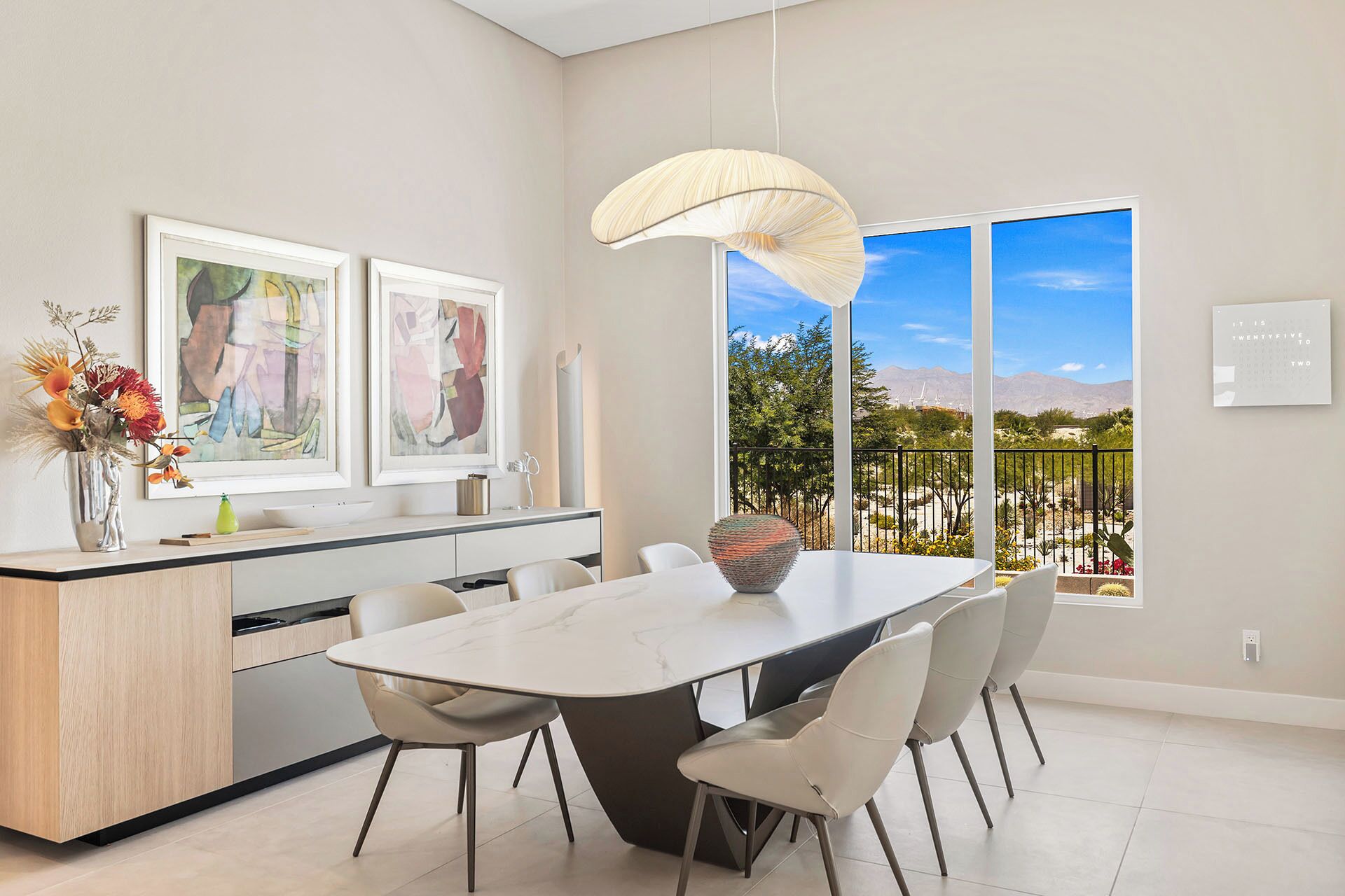 Una cocina moderna con comedor, ventanas amplias con vistas a montañas y obras de arte en las paredes.