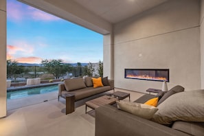 Ein moderner Außenbereich mit Pool, einer Sitzecke, einem Couchtisch und einem Kamin.