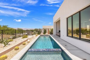A modern pool with clear water, surrounded by desert plants and a metal fence. - Solstice - A Beautifully Designed Desert Retreat (Palm Springs)