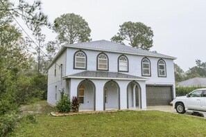 Ein zweistöckiges Haus mit Garage, Rundbogenfenstern und einer Veranda.