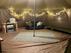 A tent interior with a bed, a small table with a heater, and string lights. - Hokkaido Hideaway: Bonfire & BBQ (Toyoura)