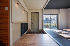 Un couloir avec un plancher en bois, une porte et une fenêtre donnant sur un paysage.