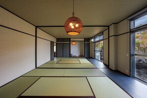 Ein traditioneller japanischer Raum mit Tatami-Bodenbelag, Schiebetüren und einer hängenden Leuchte.