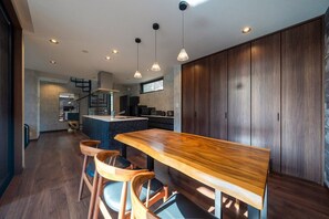 Una cocina moderna con una isla de madera, iluminación colgante y vistas al área de estar.