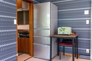 A compact kitchen with a refrigerator, a microwave, and a small table. - Private Palfaure Izu: Dual Cinema, Mineral Hot Spring & BBQ Area (Itō)