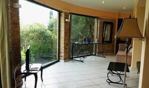 A spacious room with large windows, a glass table, a sofa, and a lamp. - The One Bedroom Villa (Zakynthos)