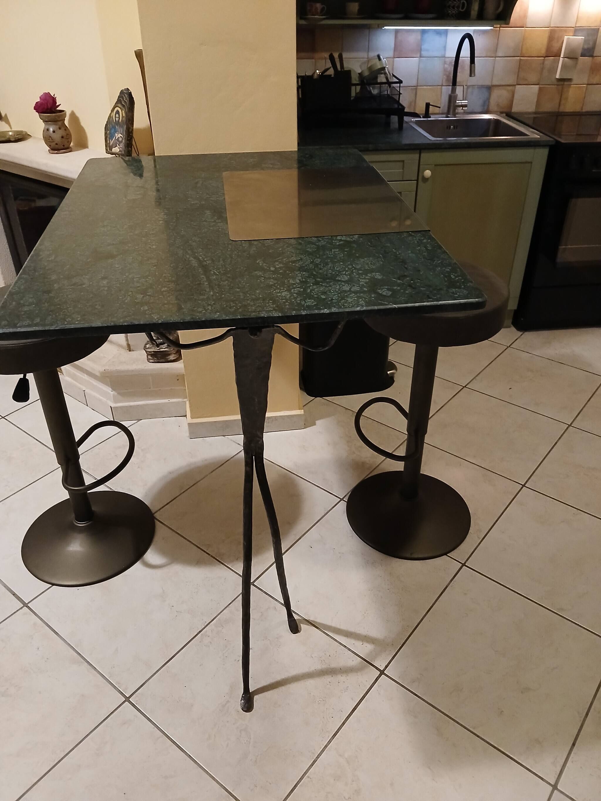 Eine Küche mit einem schwarzen Tisch, gefliestem Boden und einem Spülbecken.