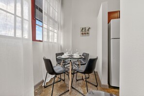 Een klein eetgedeelte met een ronde tafel, vier stoelen en een witte koelkast.