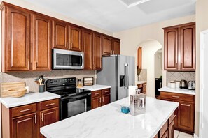 Une cuisine moderne avec des meubles en bois, un réfrigérateur en acier inoxydable, un four à micro-ondes et une cuisinière.