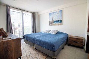 A bedroom with a bed, a desk, a painting, and a view of the sea. - King Bed Loft | 83 Mbps WiFi | Near Convention Ctr (Puerto Vallarta)