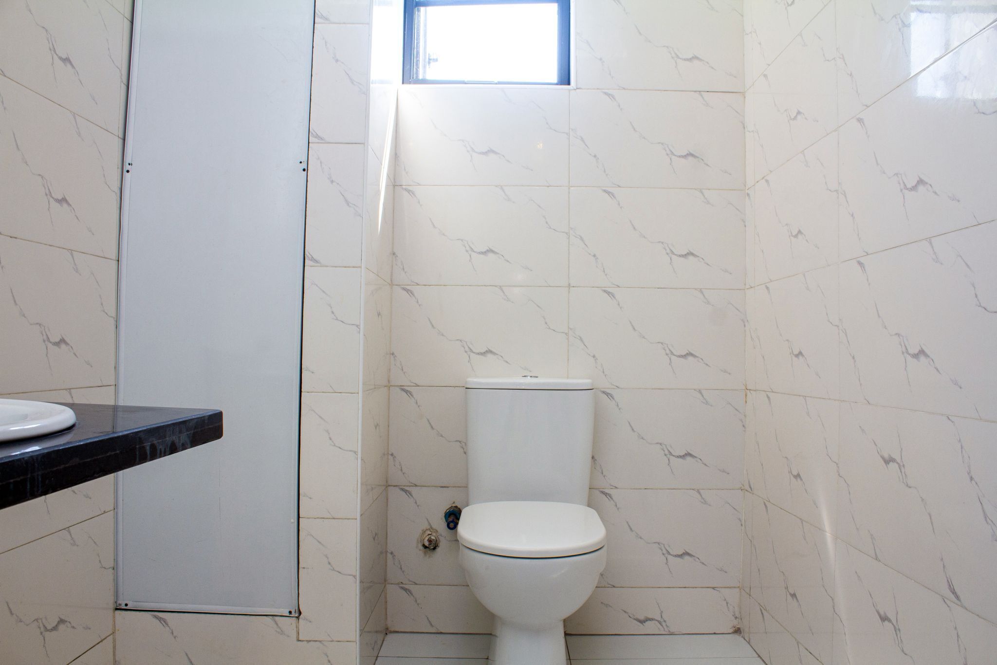 A bathroom with a toilet, a sink, and a window.