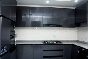 Una cocina moderna con armarios oscuros, un refrigerador de acero inoxidable, una estufa a gas y un lavavajillas.