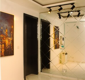 A modern interior with a glass partition, a painting of a cityscape, and a ceiling with recessed lighting. - MIO Courts (Lekki)